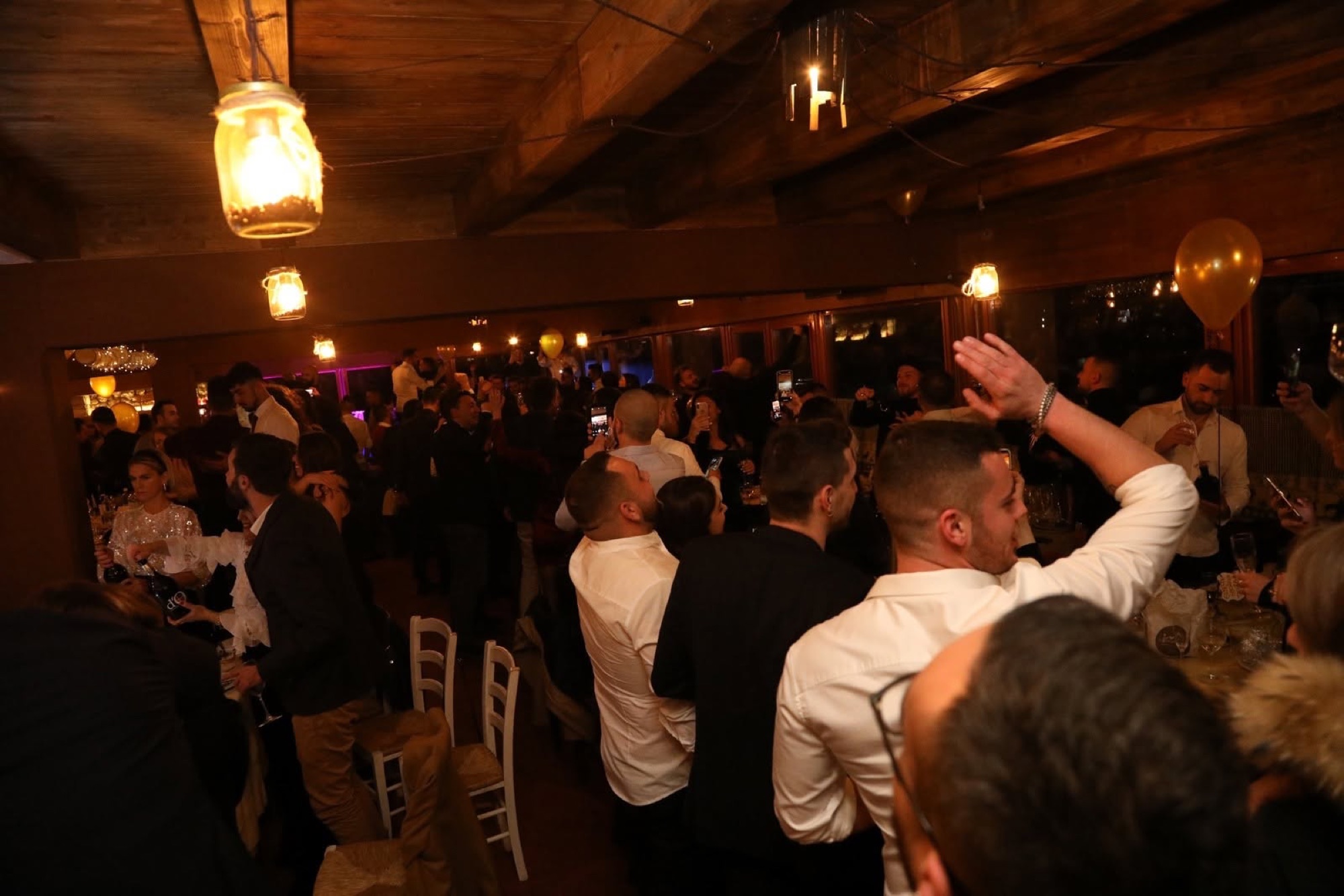 Gli ospiti brindano e festeggiano in sala a una passata edizione del Capodanno, sotto le travi di legno